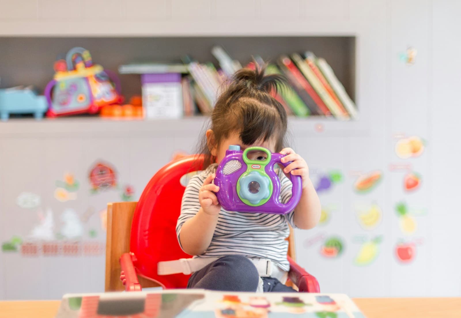 Criança brincando com uma câmera colorida em casa